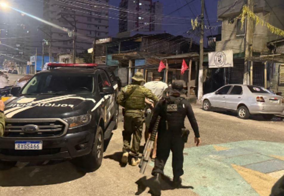 A imagem em destaque mostra policiais civis conduzindo um dos suspeitos preso.